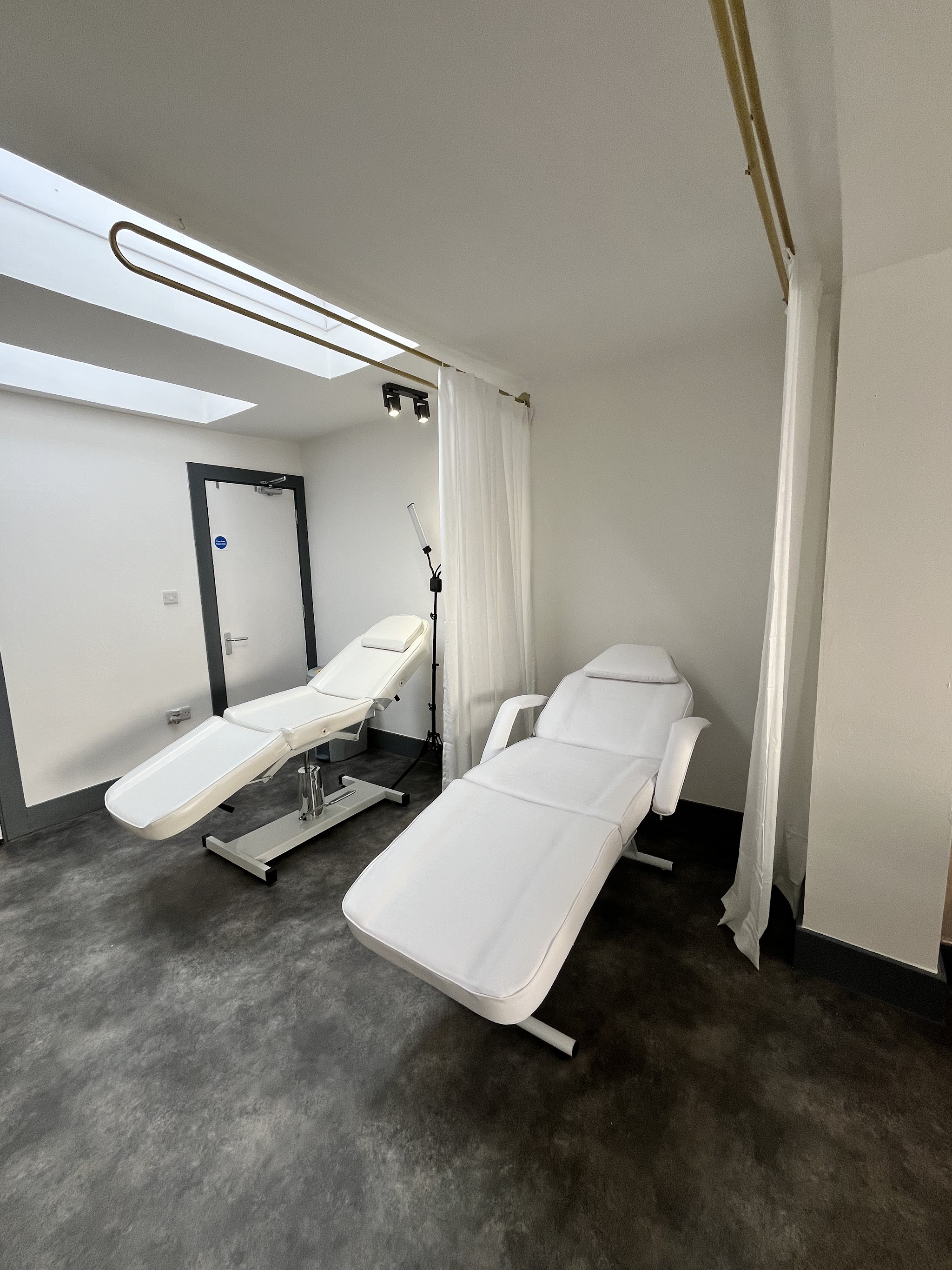 Our treatment room with two white treatment beds and a skylight