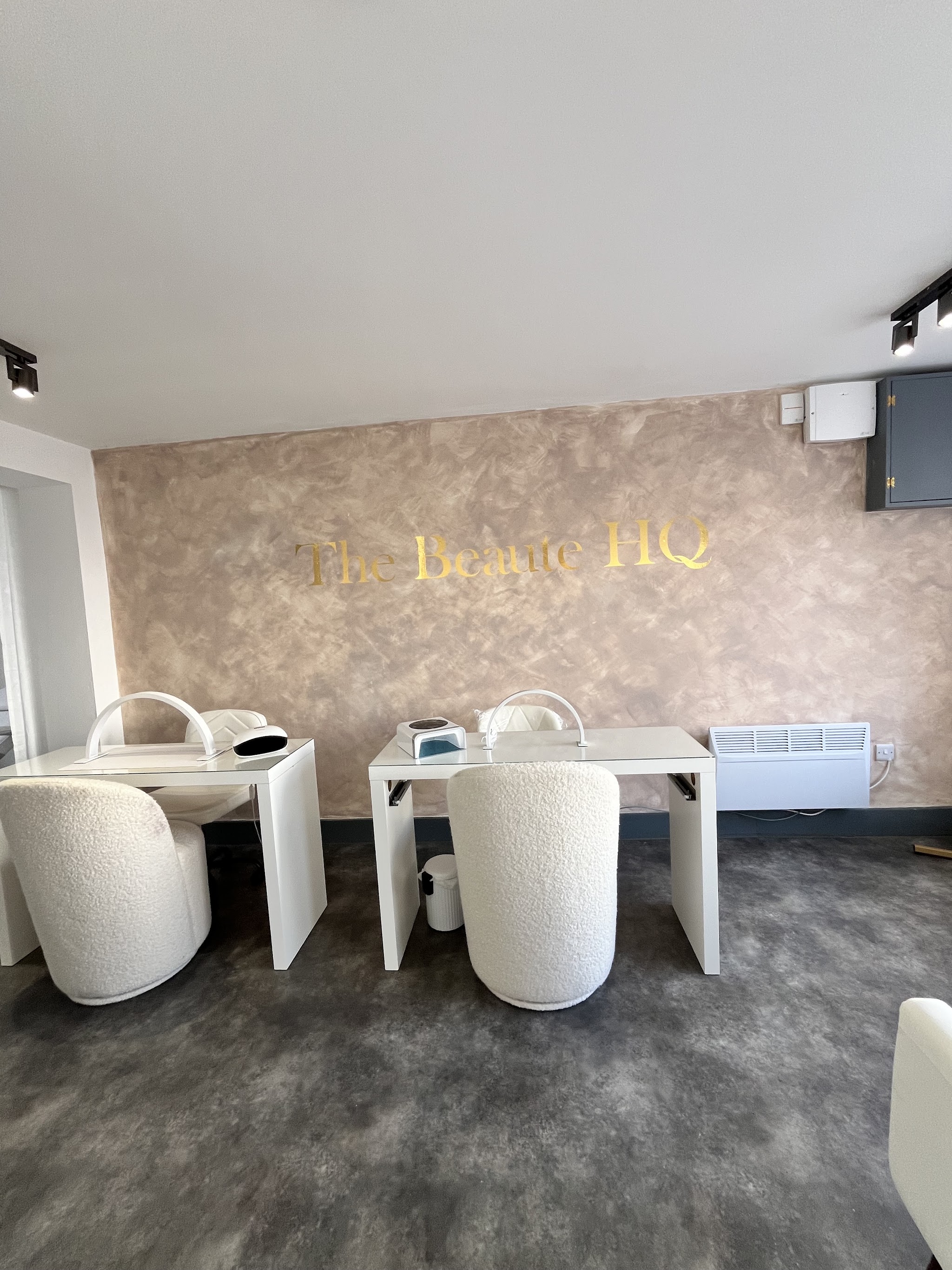 Our nail room: white nail desks and boucle chairs under the gold Beauté HQ lettering